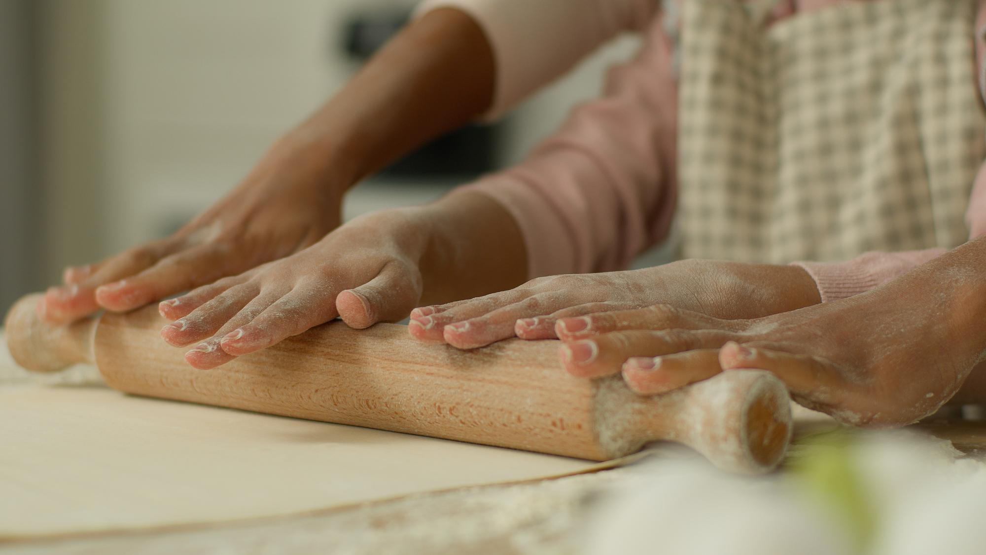 Close up of hands kneading dough on wooden table